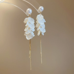 Close-up of white petal tassel earrings with pearls and long gold chain fringe details