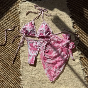 Détail à plat d'un ensemble bikini trois pièces rose paisley avec paréo assorti