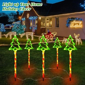 Five LED Christmas tree lawn stakes glowing green in a garden with holiday lighting