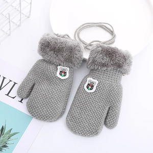 Detailed close-up of grey knitted toddler gloves with plush cuffs and a hanging neck string