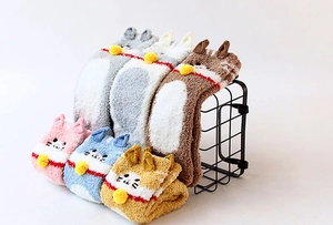 Detail of coral fleece cat socks with 3D ears and bells displayed on a metal rack