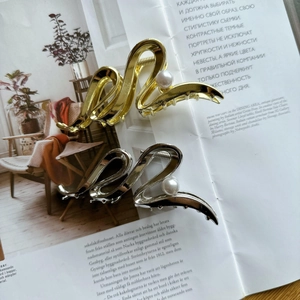 Sleek gold and silver wave shark hair clips with pearl detail on a lifestyle magazine