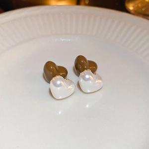 Vue macro de boucles d'oreilles cœur acrylique café et perle sur un plateau en céramique