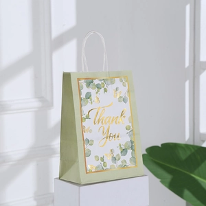 Close-up of a green kraft paper gift bag with gold foil Thank You text and leaf patterns