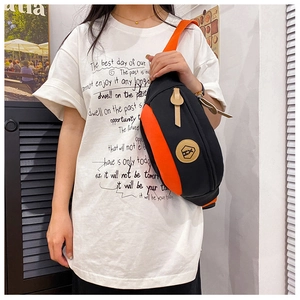 Detail shot of black and orange crossbody bag featuring durable nylon fabric and logo