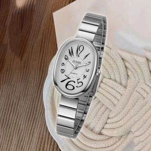 Detailed macro of oval white watch dial with silver metal strap on woven mat