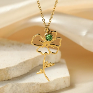 Macro detail of 18k gold flower pendant with green gemstone on stone and silk background