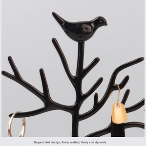 Detail of tree-shaped jewelry organizer with bird motif and hanging accessories