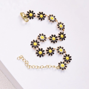 Detail of sweet daisy bracelet with black petals and gold chain on white background