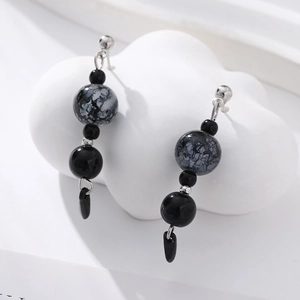 Detail of Chinese style earrings with black ink texture beads on white ceramic base