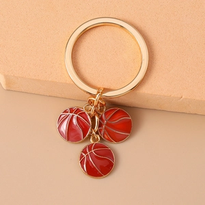 Detailed macro shot of a golden alloy keychain with three red basketball charms and oil drip finish