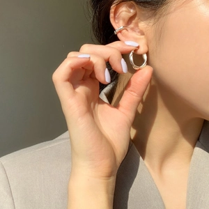 Close-up of silver 925 woven texture earrings and ear cuff on model with natural sunlight