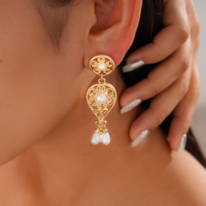 Detailed view of vintage gold hollow flower earrings with pearl drop tassels on a model