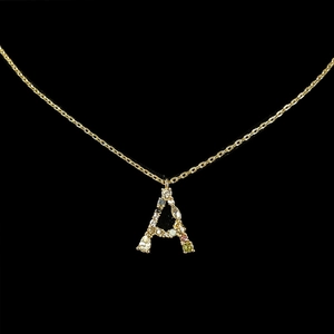 Macro shot of 18k gold letter A pendant with colorful zircon stones on black background