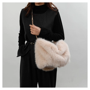 Detail view of plush beige faux fur tote bag with stylish golden metal chain strap
