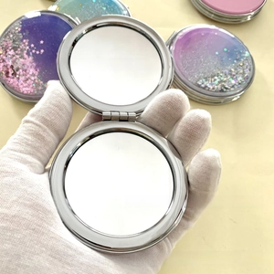 Detail of a portable round glitter quicksand makeup mirror with purple gradient finish