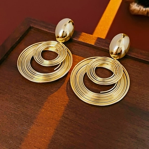 Macro shot of gold spiral circular earrings on a textured dark wood background