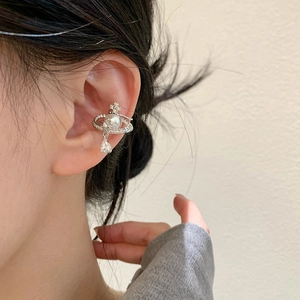 Macro shot of a silver Saturn ear cuff with a white pearl and sparkling zircon water drop