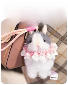 Detail of plush bunny keychain with pink lace collar on a bag handle macro view