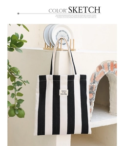 Detailed view of striped canvas tote bag with woven label on a minimalist wall