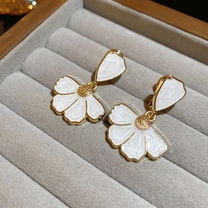 Détail de boucles d'oreilles pétales blancs avec étamines dorées dans un écrin