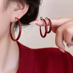 Macro detail of three sizes of red enamel round hoop earrings with elegant glossy finish