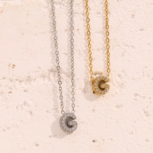 Dettaglio dei ciondoli lettera G in oro 18K e argento con cristalli scintillanti