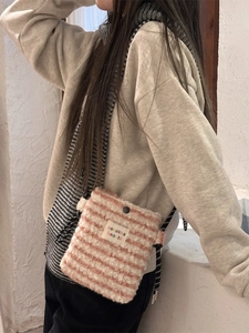 Pink and beige plush crossbody bag with striped pattern and woven strap on model