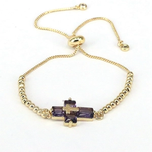 Detailed macro view of the gold bolo bracelet with purple zircon stone cross pendant