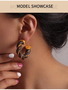 Close-up of retro C-shape earrings with twisted dark brown leather and gold metal design
