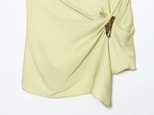 Macro detail of sage green satin fabric with golden metal buckle and gathered pleats