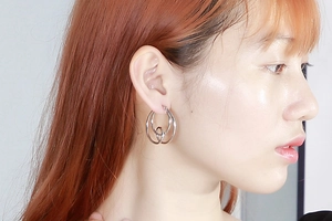Silver double-hoop knot earrings in polished stainless steel worn by a fashion model