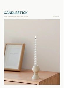 Dettaglio del candeliere in ceramica opaca beige con candela a spirale bianca su legno