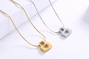 Detailed close-up of gold and silver heart-shaped lock pendants on titanium steel necklaces