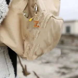 Honey bee letter Z keychain with yellow tassel hanging on a canvas backpack zipper