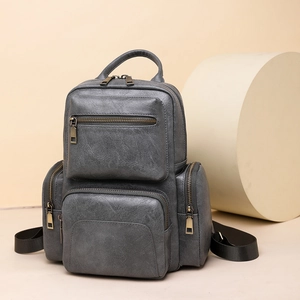 Close-up of vintage dark gray PU leather backpack with gold zippers and layered pockets