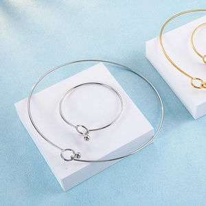Minimalist gold and silver bangle bracelets and necklaces on white geometric blocks