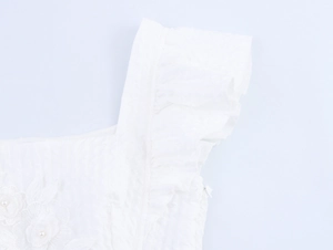 Close-up of white dress with ruffle sleeves, 3D floral embroidery and pearl accents