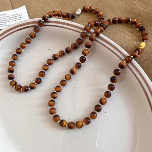 Macro shot of vintage tiger eye beaded necklace with metallic spacers in a ceramic dish