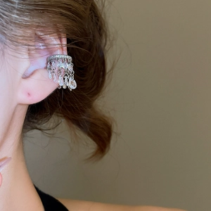 Gros plan sur l'earcuff argenté avec glands en zircone étincelante et pendentifs