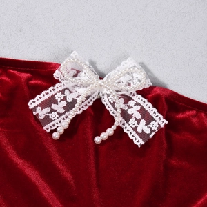 Macro detail of red velvet dress featuring white lace bow and elegant faux pearl charms