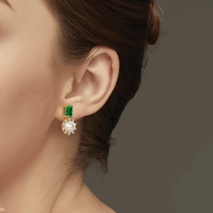 Detail shot of vintage s925 silver earring with emerald cut green gem and pearl charm