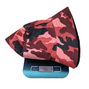 Détail d'un chapeau bob camouflage pesant 74 grammes sur une balance électronique bleue