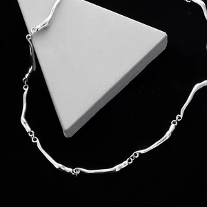 Silver twisted wavy link necklace made of titanium steel on geometric display stand