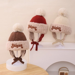 Detalle de gorros de invierno cálidos con pompones y forro de piel sintética en tres colores