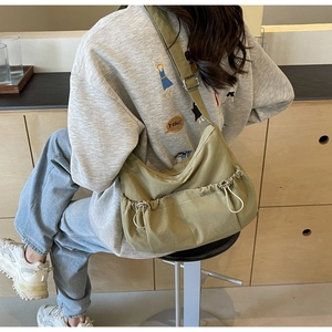Detail of khaki nylon pleated crossbody bag with drawstring design and wide shoulder strap