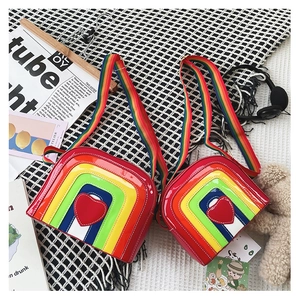 Detail shot of heart rainbow crossbody bags with colorful striped strap on a styled background