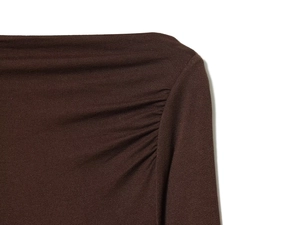 Gros plan sur la texture du tricot marron foncé et les détails plissés de l'épaule