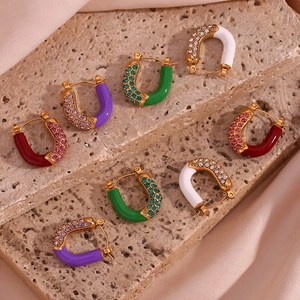 Detailed close-up of U-shaped gold earrings with colorful enamel and zircon on stone