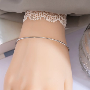 Close-up of a minimalist silver metal bangle on wrist with elegant lace sleeve detail